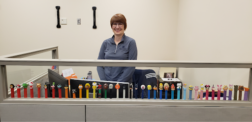 Laura behind her desk displayed with her PEZ collection.